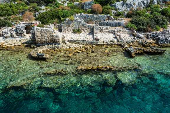 Ruins on the edge of the water and some submerged between the crystal clear water
